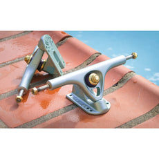Pair of Paris V3 180mm 50° longboard trucks in crystal blue with gold hardware and purple bushings on wet tiles. - Longboards USA