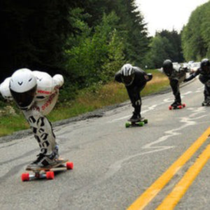Downhill Longboarders going fast on a road with trees in the background