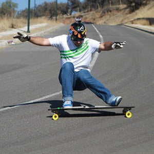 Person skateboarding on a road with a clear sky and trees in the background