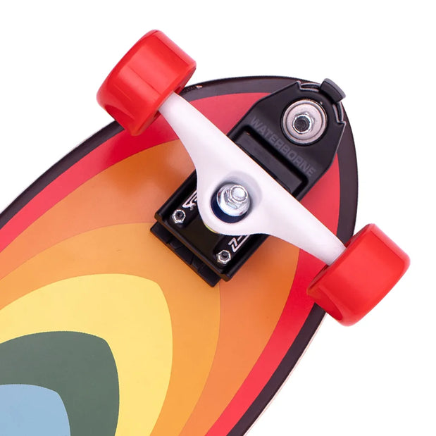 Close-up of Z-Flex Surf-A-Gogo 31-inch surfskate cruiser with red wheels, white truck and retro rainbow deck. - Longboards USA